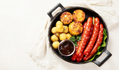 Grilled meat sausages in a pan with vegetables.