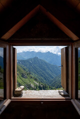 The view the green mountains from the window in a small hut, Bivacco, in the Italian Alps.