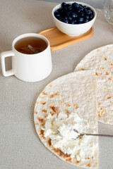 Cup of tea and lavash with curd cheese for breakfast.