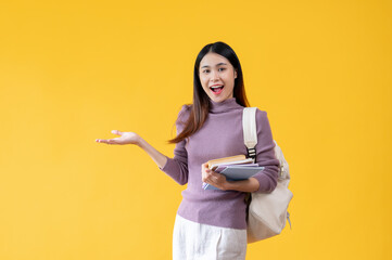 A pretty Asian female college student opening her palm, an isolated yellow background.