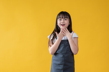 A cheerful Asian girl is standing and showing a surprised and happy facial expression.