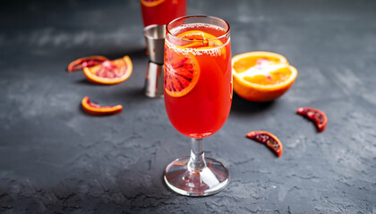 Red orange juice in a large glass or blood orange sparkling vodka cocktail or aperitif with campari...