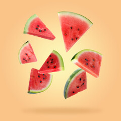Slices of fresh juicy watermelon falling on coral background