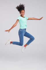 Taking fashion to new heights, a woman leaps in mint shirt and blue jeans, bringing an exciting dynamic to the studio pose.