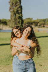 Dos chicas jóvenes juntas sonriendo y disfrutando dandose abrazados y mostrando cariño. Hermanas...