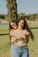 Dos chicas jóvenes juntas sonriendo y disfrutando dandose abrazados y mostrando cariño. Hermanas pasando dia en familia.