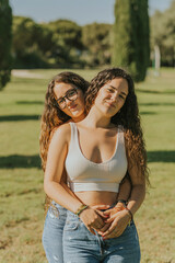 Dos chicas jóvenes juntas sonriendo y disfrutando dandose abrazados y mostrando cariño. Hermanas...