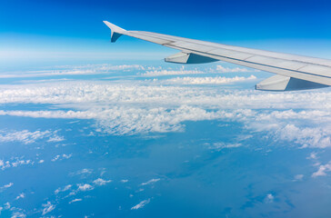 View from the airplane window at a beautiful cloudy sky and the airplane wing