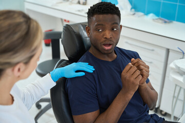 Frightened African American patient can't open mouth for teeth health check-up