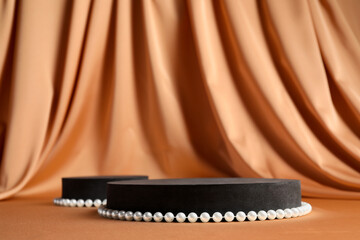 Black geometric figures and pearls on light brown table, space for text. Stylish presentation for...
