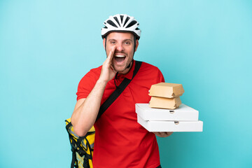 Young caucasian man with thermal backpack and holding fast food isolated on blue background shouting with mouth wide open