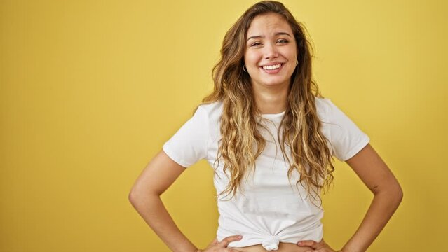 Young beautiful hispanic woman smiling confident standing clueless over isolated yellow background
