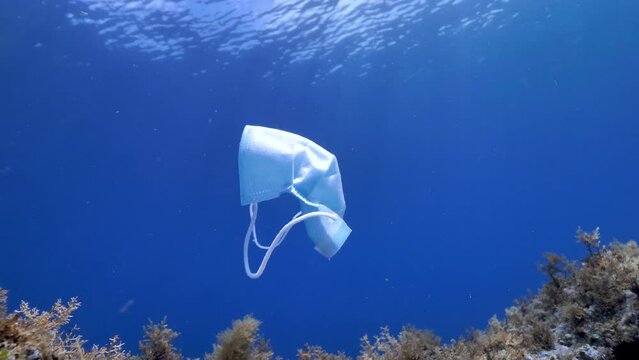 Mascarilla flotando en el agua. Contaminaci&oacute;n del mar