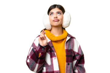 Young Russian woman wearing winter muffs over isolated chroma key background with fingers crossing and wishing the best