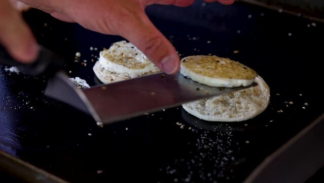 Breakfast sandwich being put together on a hot cast iron griddle.