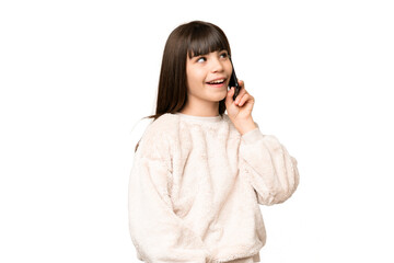 Fototapeta premium Little girl over isolated green chroma key background keeping a conversation with the mobile phone