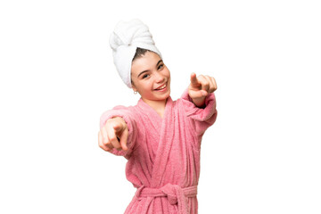 Little girl in a bathrobe over isolated chroma key background points finger at you while smiling