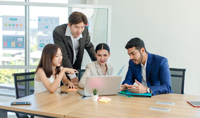 Millennial Asian Indian multinational professional successful businessmen and businesswomen in formal suit helping brainstorming working as teamwork via laptop notebook computer in company office