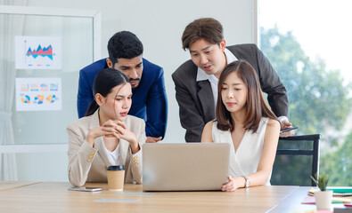 Asian Indian multinational professional successful male businessmen and female businesswomen in formal business wear working discussing brainstorming via laptop notebook computer in company office