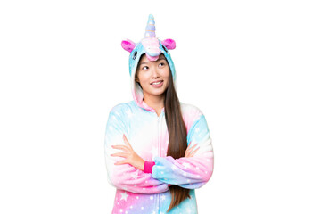 Young Asian woman with unicorn pajamas over isolated chroma key background looking up while smiling