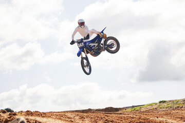 Fototapeta na wymiar Sports, jump and man on motorcycle with freedom, energy and power stunt in the countryside for training challenge. Off road, air and male jumping with motorbike for speed, performance or Moto action