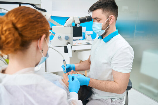 Doctor Treats A Young Female Tooth Under A Microscope