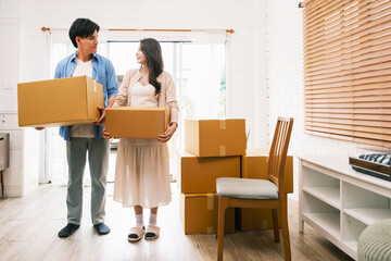 Fototapeta na wymiar Asian young happy new married couple moving to their new house or real estate. An attractive romantic man and woman carry boxes parcel with happiness and love. Family moving house relocation concept.