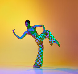 Young artistic, talented woman dancing contemporary, freestyle dance against gradient yellow orange...