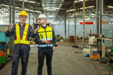 Two professional engineer worker technician assistant in helmet inspection check old machine construction factory with colleague manager. check old machinery production construction operating