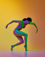 Fototapeta na wymiar Tender young woman in underwear dancing contemp dance against gradient yellow orange background in neon light. Concept of modern dance style, hobby, art, performance, lifestyle, ad