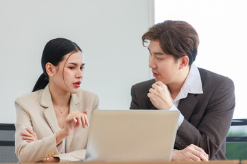 Obraz premium Asian professional successful male businessman explaining discussing brainstorming with female businesswoman colleague in formal business suit via laptop notebook computer in office company workplace