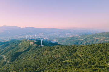 Aerial view of nature with eco-friendly wind turbines power plant in mountain at sunset