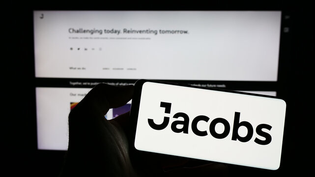 Stuttgart, Germany - 07-29-2023: Person holding smartphone with logo of US services company Jacobs Solutions Inc. on screen in front of website. Focus on phone display.