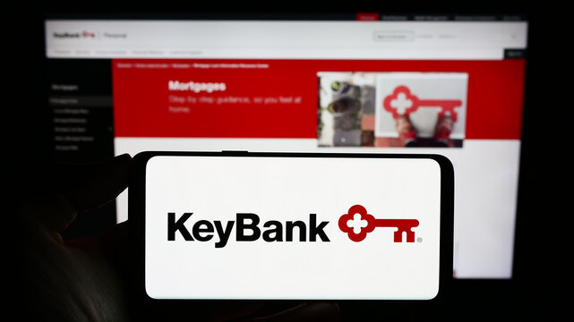 Stuttgart, Germany - 07-30-2023: Person holding mobile phone with logo of American financial company KeyCorp (KeyBank) on screen in front of web page. Focus on phone display.