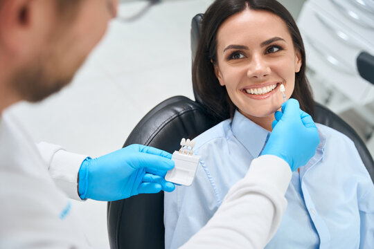 High-qualified dental technician choosing proper size and color of dental crown