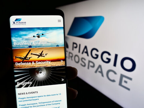 Stuttgart, Germany - 07-30-2023: Person holding mobile phone with web page of Italian company Piaggio Aero Industries S.p.A. on screen with logo. Focus on center of phone display.