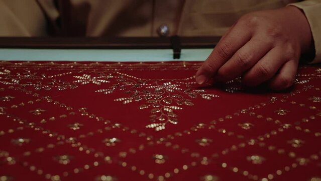 handcrafting traditional red headscarf shawl keringkam using embroidery with gold threads intricately