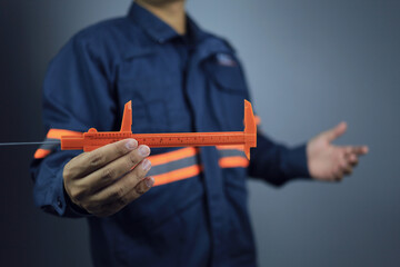 An engineer or technician is holding a vernier caliper to measure length or dimensions that require...