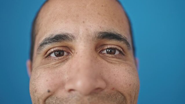 Young hispanic man close up of eyes smiling over isolated blue background