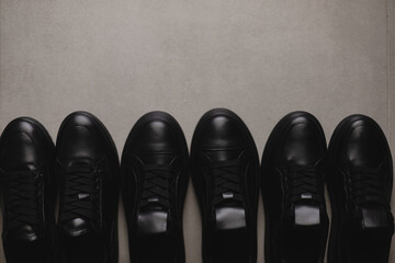 Three pairs of black sneakers on the floor. Casual fashion style minimalistic shoes.