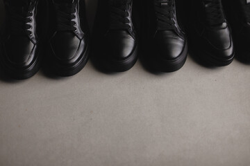 Three pairs of black sneakers on the floor. Casual fashion style minimalistic shoes.