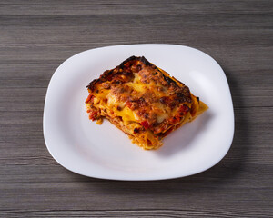 plate with lasagna on gray wooden table. typical Italian cuisine
