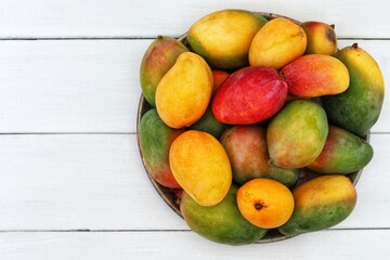 Many mangoes on the table, exotic fruits, wooden background, top view, free space, place for text, background image, tropical sweets