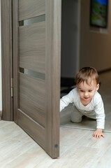 Curious baby exploring through a doorway. A baby crawling through a door on the floor