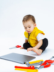 Baby playing with tools on the floor. A baby sitting on the floor playing with tools