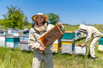 Photo of a man holding a beehive in a field