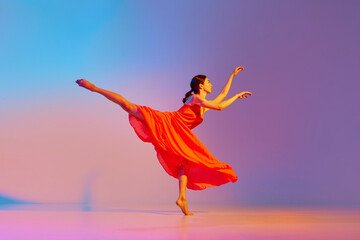 Grace and tenderness. Young beautiful woman in long elegant dress dancing against gradient...