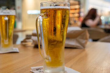 Cerveza en vaso frío tomada en una terraza de interior. Fondo desenfocado.