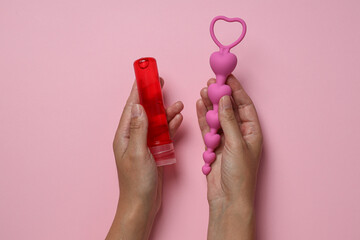 Lubricant with anal balls in hands on pink background - obrazy, fototapety, plakaty