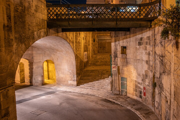 the empty streets of Valletta at night. Street lights illuminate the old houses